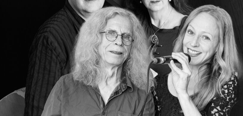 Schwarzweiß-Foto von der Band, vier Personen schauen in die Kamera