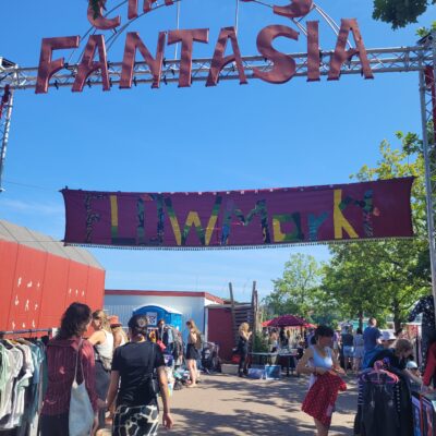 Flohmarktstände unter dem Eingangsbereich des Circus Fantasia Platzes, über dem der Schriftzug "Circus Fantasia" ragt