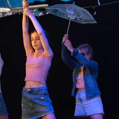 Mädchen halten einen durchsichtigen Regenschirm nach oben und choreografieren gemeinsam einen Tanz