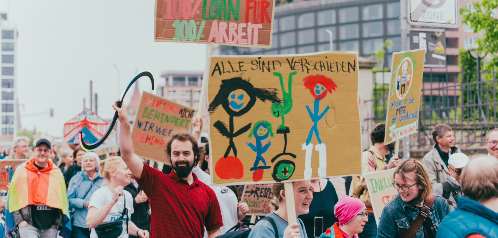 Menschen halten Schilder für Inklusion und Teilhabe in die Luft und demonstrieren gemeinsam