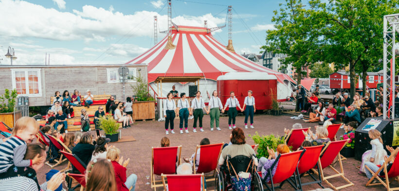 Menschen tummeln sich auf dem Platz des Circus Fantasia und bestaunen eine Aufführung
