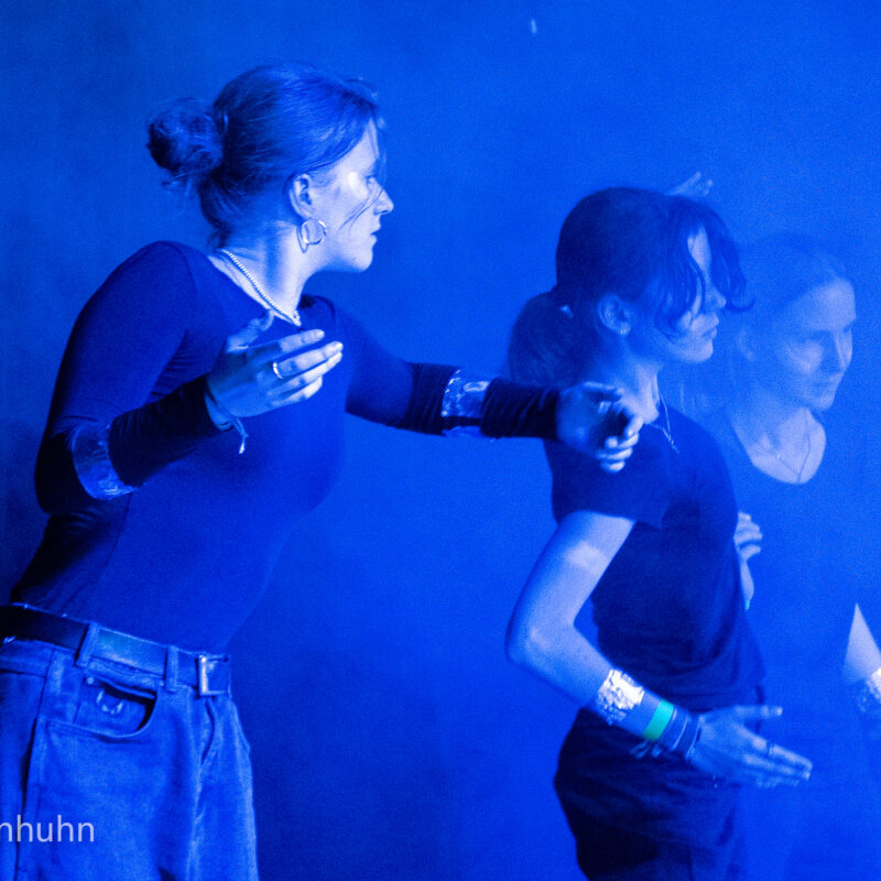 3 Mädchen tanzen gemeinsam, umhüllt von Nebel und blauem Licht
