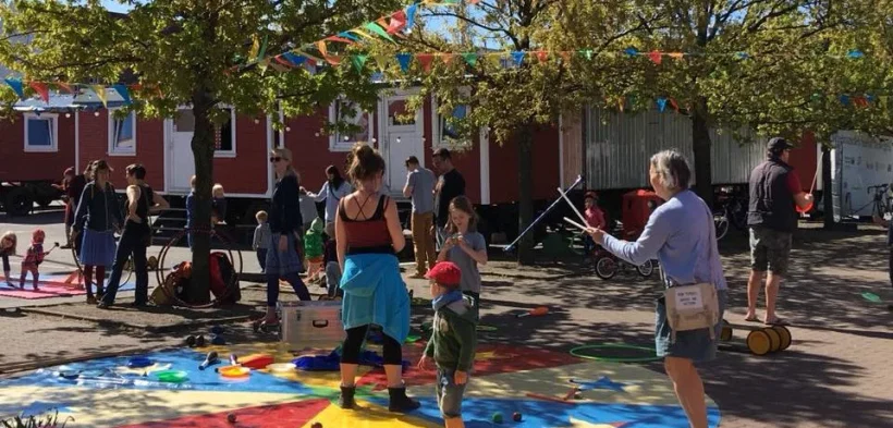 Kinder und Erwachsene stehen auf dem Platz des Circus Fantasia und probieren verschiedene Circusdisziplinen aus.